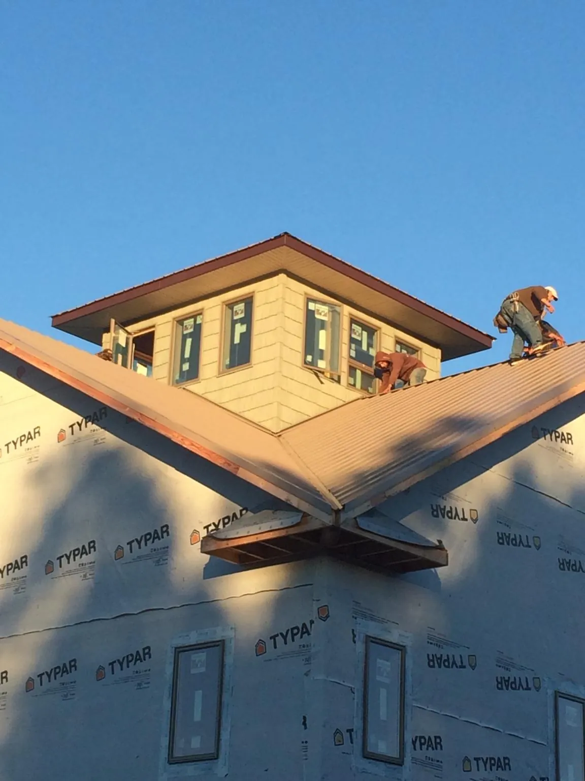 Roofers working around a rooftop cupola on a new metal roof at sunset — Roof Waterproofing in Exeter by Roofing Brothers